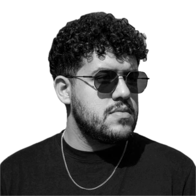 Portrait of Micael Marques, with curly hair, a beard and sunglasses.